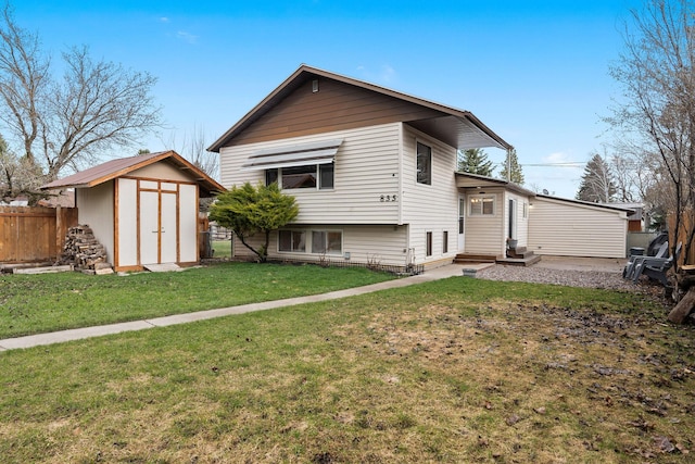 rear view of property featuring an outdoor structure, entry steps, a storage shed, fence, and a lawn
