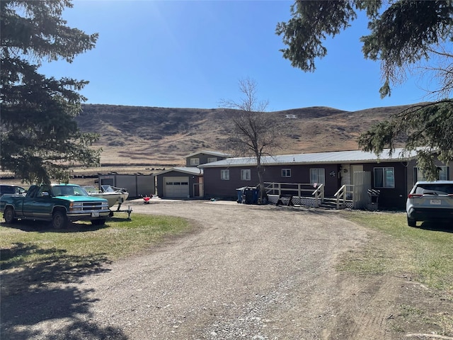 view of front of property with dirt driveway, covered porch, a mountain view, and a garage