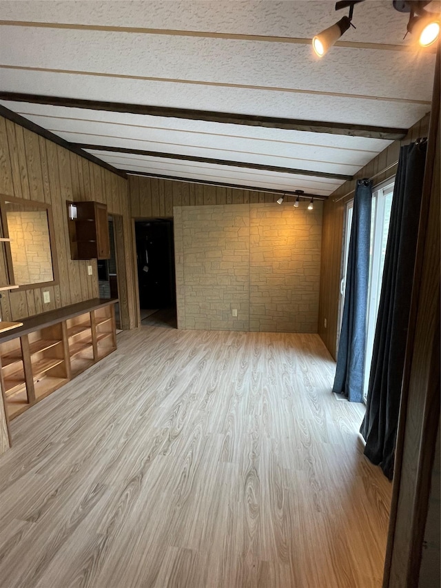 381 Lyng Ave W, Highwood, MT 59450 - unfurnished living room featuring wood finished floors, beamed ceiling, wooden walls, brick wall, and track lighting