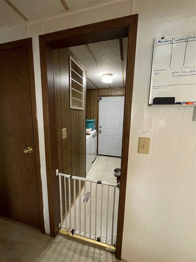 hall with wood walls and separate washer and dryer