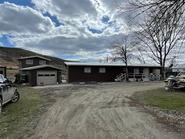 view of front of house featuring dirt driveway and an attached garage