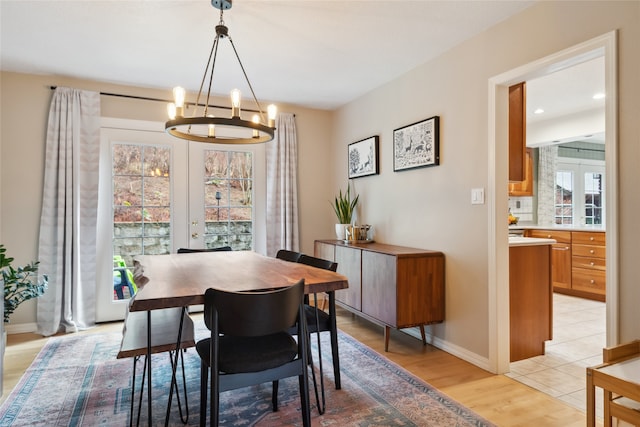 dining area featuring a chandelier, light wood-type flooring, and baseboards