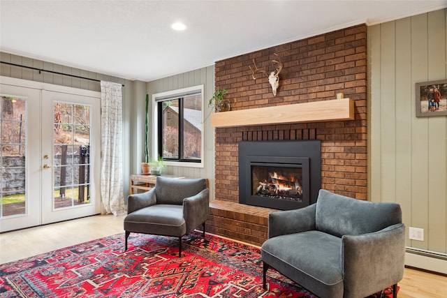 sitting room with french doors, wood finished floors, a brick fireplace, baseboard heating, and recessed lighting