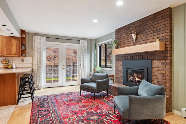 living room featuring french doors, light wood-style floors, a fireplace, recessed lighting, and a baseboard radiator