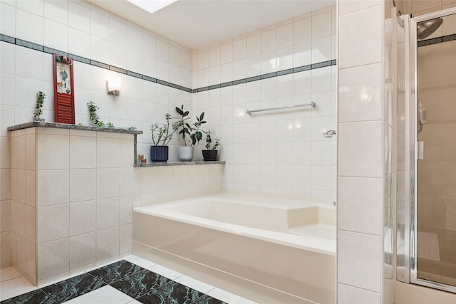 bathroom featuring tile walls, a stall shower, a bath, and marble look tiles