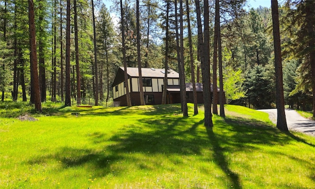 view of front of home featuring a front yard and a forest view