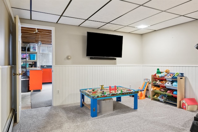 rec room featuring a baseboard heating unit, wainscoting, a drop ceiling, and carpet floors