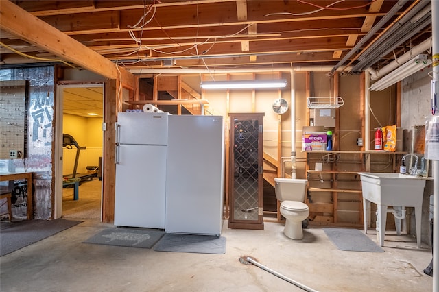 unfinished basement with freestanding refrigerator