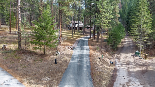 view of asphalt driveway featuring a wooded view