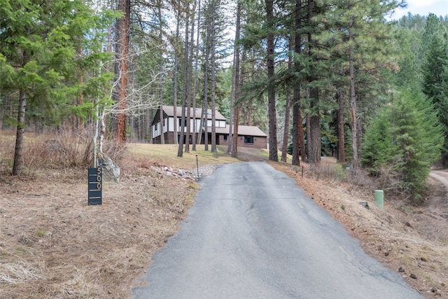 view of asphalt driveway featuring a wooded view