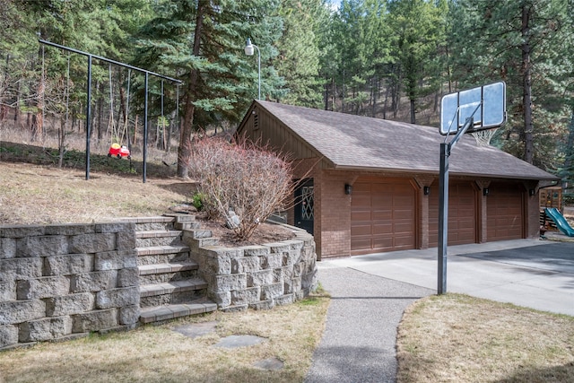 view of home's exterior with roof with shingles, brick siding, and driveway