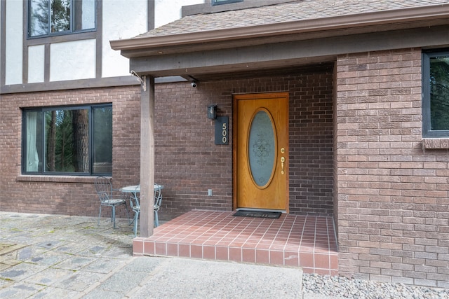 view of exterior entry featuring brick siding and stucco siding