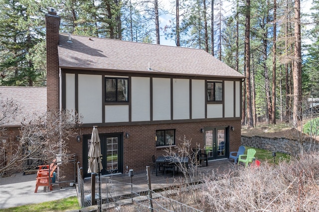 rear view of house with a chimney, a patio area, roof with shingles, and french doors