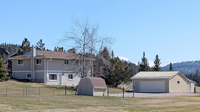 view of home's exterior with a yard, an outbuilding, and fence
