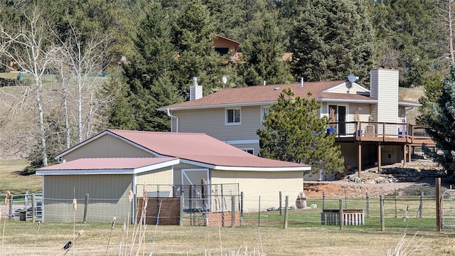 rear view of property featuring fence, a pole building, a chimney, and a wooden deck