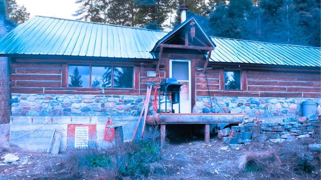 view of front of property with metal roof, log siding, and stone siding