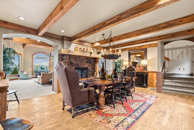 31572 Lake To Sky Dr, Bigfork, MT 59911 - dining space with wood finished floors, beam ceiling, stairs, a fireplace, and arched walkways