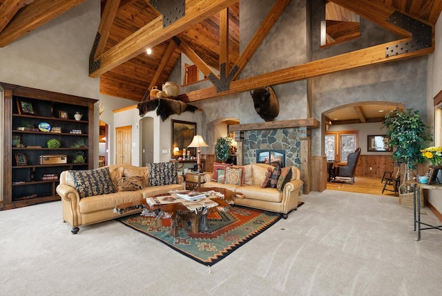 31572 Lake To Sky Dr, Bigfork, MT 59911 - carpeted living area with arched walkways, high vaulted ceiling, beam ceiling, a stone fireplace, and wooden walls