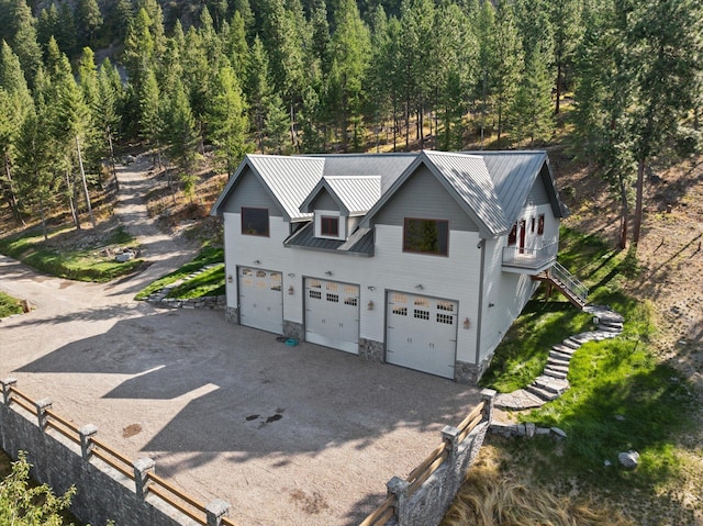 31572 Lake To Sky Dr, Bigfork, MT 59911 - view of front of home featuring stairway, a wooded view, a metal roof, and a garage