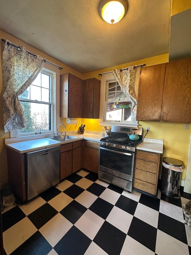 815 3rd Ave E, Kalispell, MT 59901 - kitchen featuring appliances with stainless steel finishes, a sink, light flooring, light countertops, and brown cabinetry