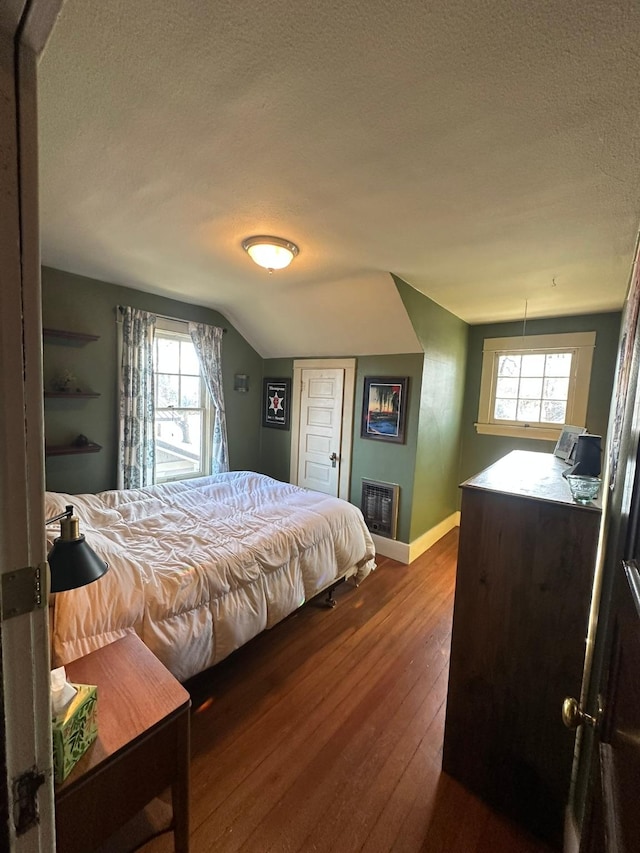 815 3rd Ave E, Kalispell, MT 59901 - bedroom featuring a textured ceiling, hardwood / wood-style flooring, heating unit, baseboards, and lofted ceiling