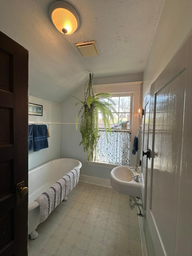 815 3rd Ave E, Kalispell, MT 59901 - full bathroom with tile patterned floors, a soaking tub, a textured ceiling, baseboards, and lofted ceiling