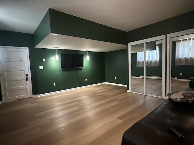 815 3rd Ave E, Kalispell, MT 59901 - unfurnished living room featuring baseboards, wood finished floors, and a baseboard heating unit
