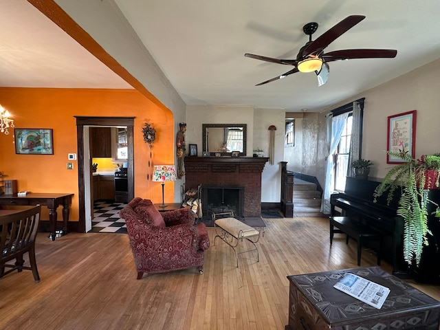 815 3rd Ave E, Kalispell, MT 59901 - living room featuring a ceiling fan, hardwood / wood-style flooring, a brick fireplace, baseboards, and a chandelier