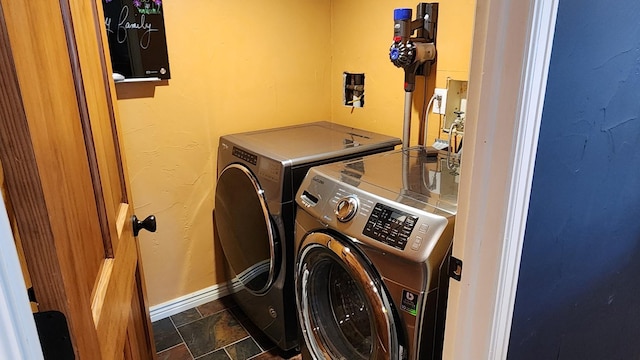 laundry room with baseboards, laundry area, washing machine and dryer, and stone finish flooring
