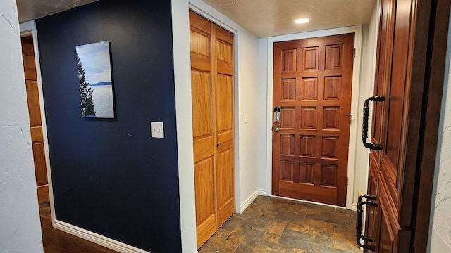 entrance foyer featuring baseboards and stone finish floor