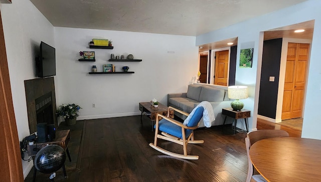 living area featuring wood-type flooring, a fireplace with raised hearth, baseboards, and recessed lighting