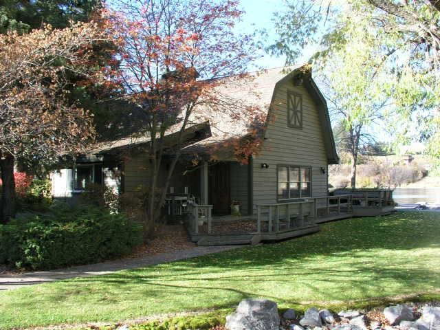 view of side of home featuring a lawn, a wooden deck, and a gambrel roof
