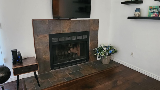 interior details featuring baseboards, a tile fireplace, and wood finished floors