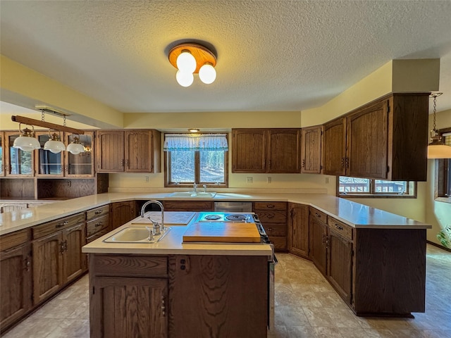 306 Parker Lakes Rd, Bigfork, MT 59911 - kitchen featuring a sink, light countertops, a peninsula, a center island with sink, and a textured ceiling
