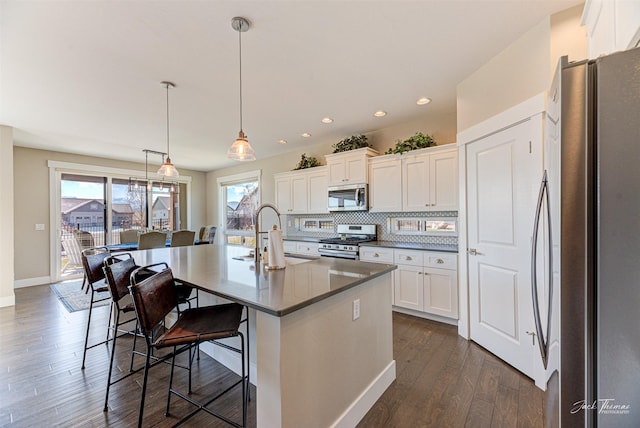 2883 Alpine View Loop, Helena, MT 59601 - kitchen with appliances with stainless steel finishes, a sink, white cabinetry, a breakfast bar area, and tasteful backsplash