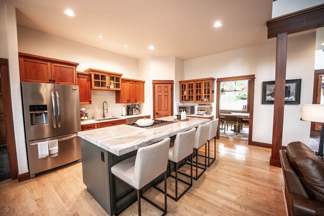 255 Windsor Ct, Bigfork, MT 59911 - kitchen with appliances with stainless steel finishes, a sink, glass insert cabinets, a kitchen breakfast bar, and light wood-style flooring
