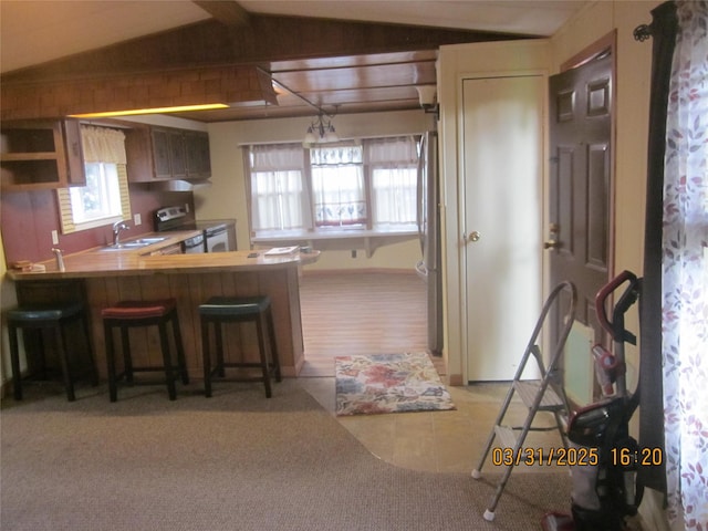 4612 Richlie St, Missoula, MT 59808 - kitchen featuring stainless steel electric range, lofted ceiling, a kitchen breakfast bar, light tile patterned floors, and light carpet