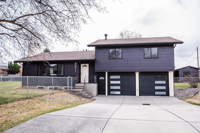 tri-level home with driveway, roof with shingles, a garage, and fence
