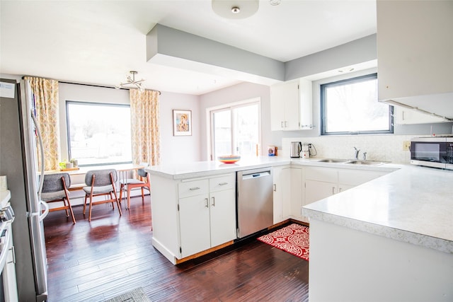 kitchen featuring appliances with stainless steel finishes, a peninsula, plenty of natural light, and a sink