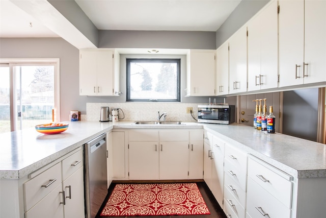 kitchen featuring stainless steel appliances, a healthy amount of sunlight, a peninsula, and a sink