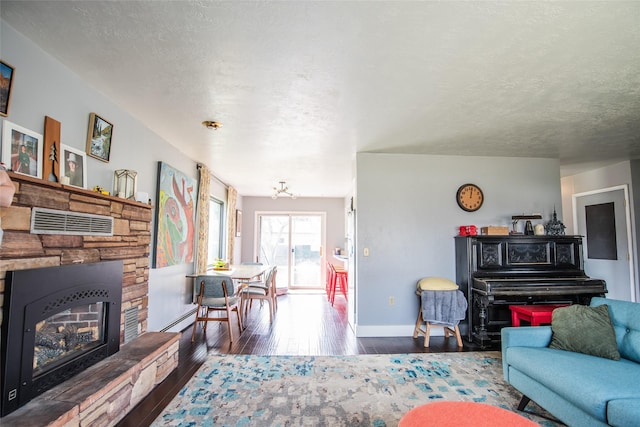 living area featuring a baseboard radiator, hardwood / wood-style floors, baseboards, a fireplace, and a notable chandelier