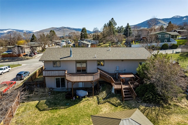 back of house with a deck with mountain view, stairs, a yard, fence, and a shingled roof