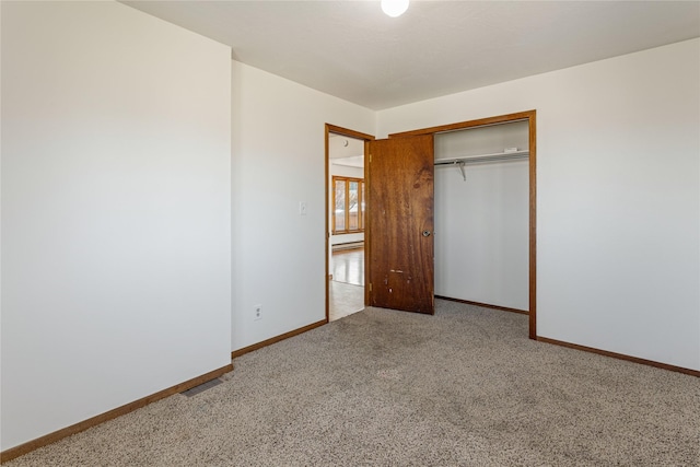 unfurnished bedroom with a closet, carpet, and baseboards