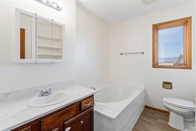 bathroom featuring a bath, baseboards, toilet, vanity, and wood finished floors