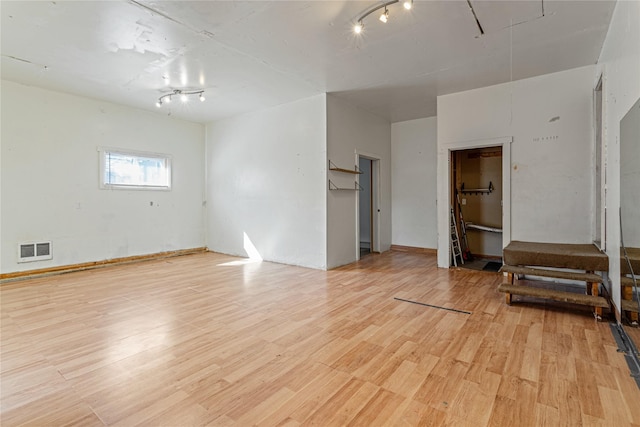unfurnished room with visible vents, light wood-style flooring, and attic access