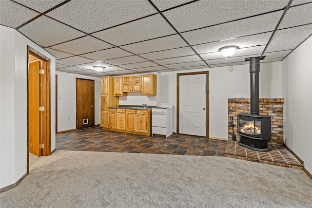kitchen with dark colored carpet, a paneled ceiling, a wood stove, and white range