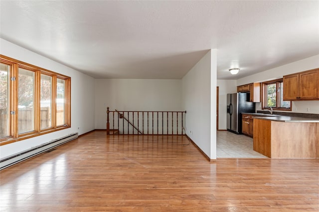 kitchen featuring a baseboard heating unit, brown cabinets, light wood-type flooring, and refrigerator with ice dispenser