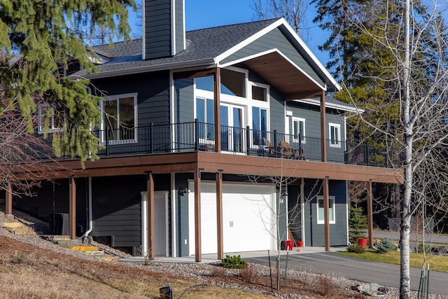 304 Stumptown Loop, Whitefish, MT 59937 - back of house featuring a chimney, a shingled roof, an attached garage, and driveway