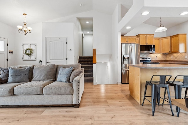 425 Northridge Dr, Kalispell, MT 59901 - kitchen featuring light wood-type flooring, vaulted ceiling, a breakfast bar, appliances with stainless steel finishes, and open floor plan