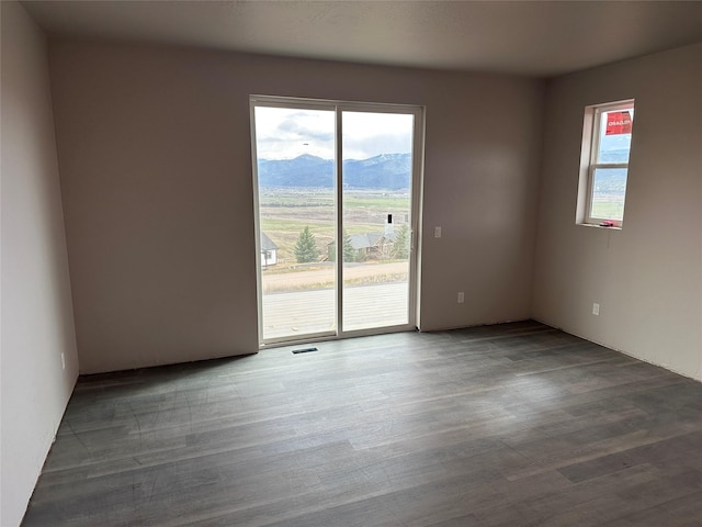 empty room with visible vents, wood finished floors, and a mountain view